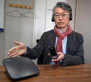 　「オーラキャスト」の機器を手にする東京工科大の吉岡英樹講師＝東京都港区