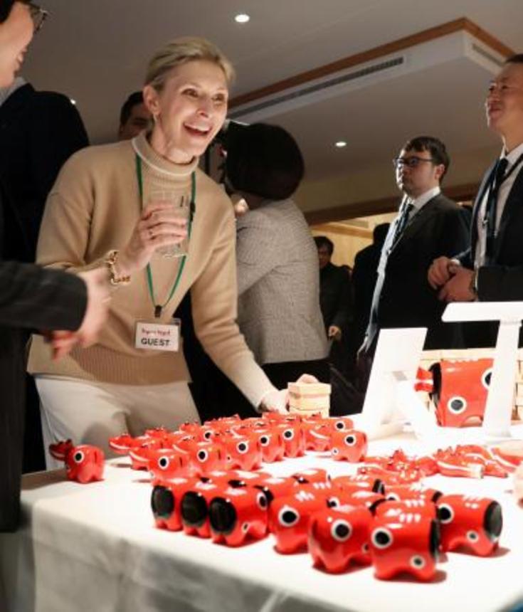 　福島県の郷土玩具「赤べこ」を前に笑顔を見せる来場者＝２１日、スイス東部ダボス（共同）