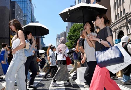　日傘を差して東京・銀座を歩く人たち。都心は今年初の真夏日となった＝１７日午後