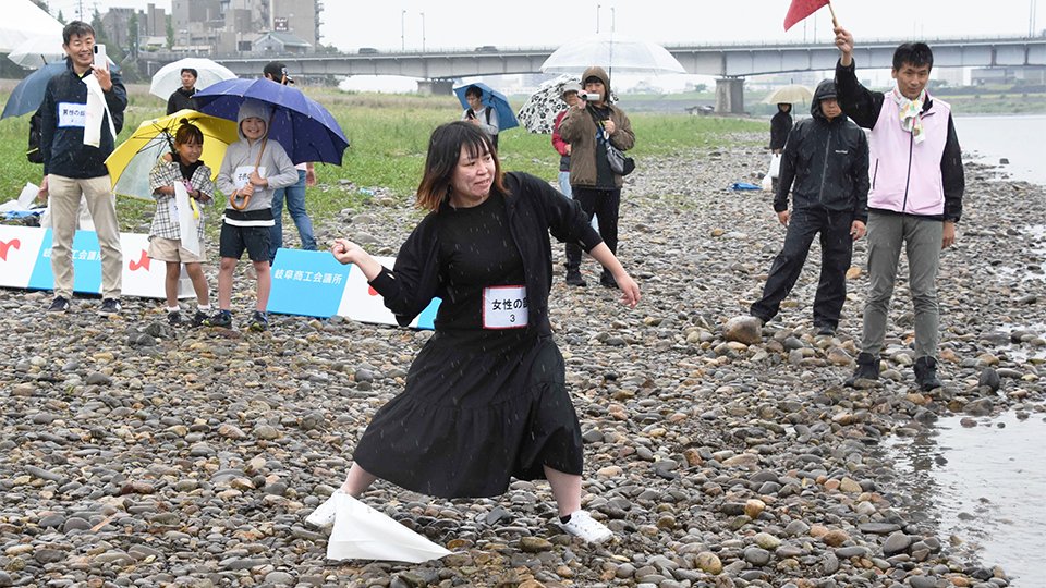 水面めがけて石を投げる参加者＝岐阜市、長良川左岸