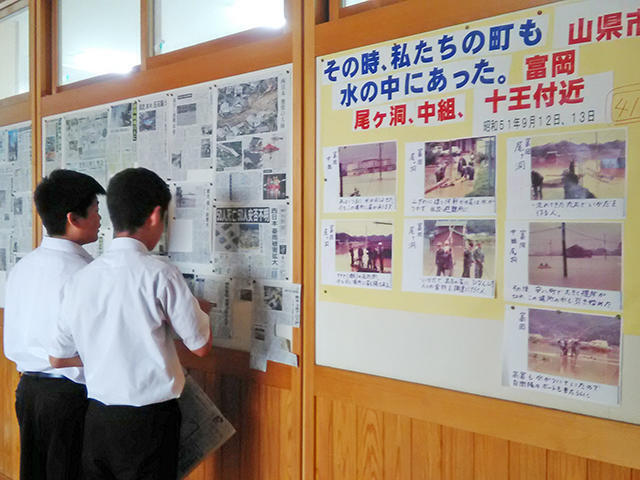 西日本豪雨の状況を伝える新聞各紙を掲示。１９７６年９月の豪雨水害の記録写真も紹介＝山県市高富、高富中学校