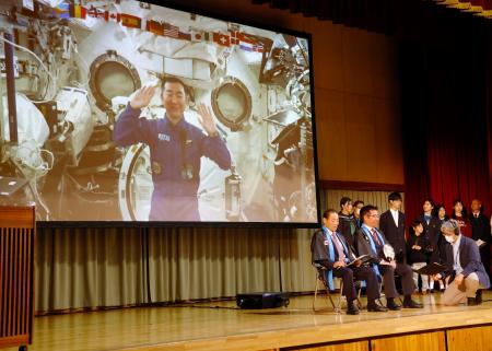 　母校の村立川上中で開かれたイベントで、宇宙から村民らと交信する油井亀美也さん（画面）＝１７日夜、長野県川上村