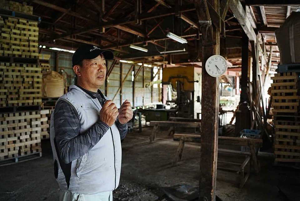製材品が積まれた倉庫で話す安達弘幸さん＝同綾部市