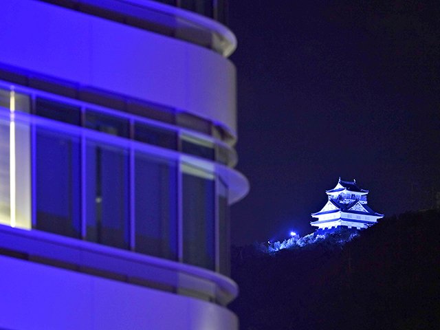 糖尿病啓発で青色に照らし出された岐阜城と岐阜市役所庁舎（手前）＝５日午後５時４６分、岐阜市内