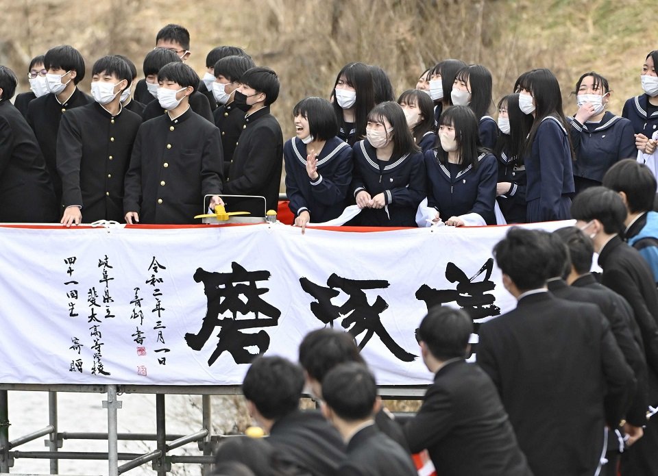 伝統の「白線流し」で対岸の恩師らにメッセージを送る卒業生ら＝１日午後０時５７分、高山市大新町、大八賀川