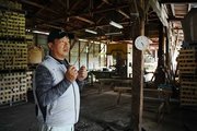 製材品が積まれた倉庫で話す安達弘幸さん＝同綾部市