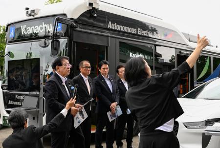 　自動運転の実証運行で使われたバスの前で、事業者から説明を受ける金子国交相（左端）＝８日午後、国交省前