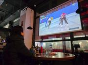 　韓国仁川市のパブで、ケーブルテレビ局が放送するミラノ・コルティナ冬季五輪の競技を見る市民＝１０日（共同）