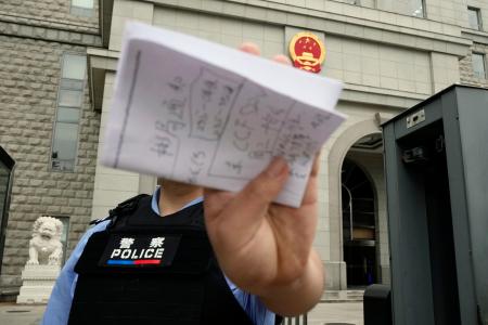 　スパイ罪で起訴された日本人男性の判決公判が開かれた北京市の第２中級人民法院前で撮影を阻止する警察官＝１６日（共同）