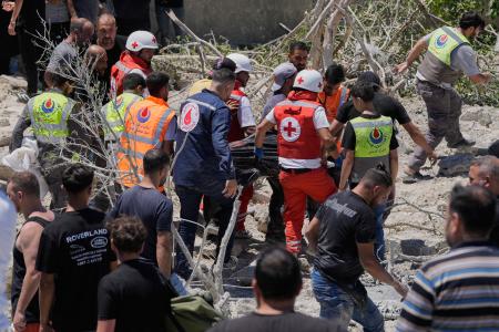 　２０日、レバノン南部でイスラエルによる空爆で破壊された建物の下から見つかった被害者を搬送する人たち（ＡＰ＝共同）
