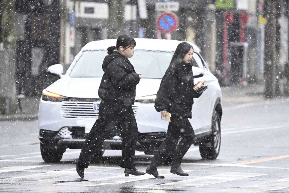 雪が降る中、横断歩道を渡る人たち＝４日午前８時４８分、岐阜市若宮町