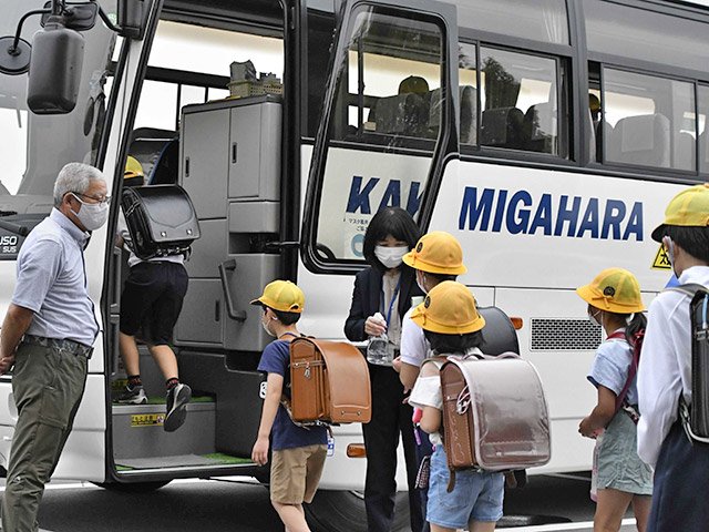 手指を消毒してバスに乗り込む子どもたち＝各務原市川島笠田町、河川環境楽園東口駐車場