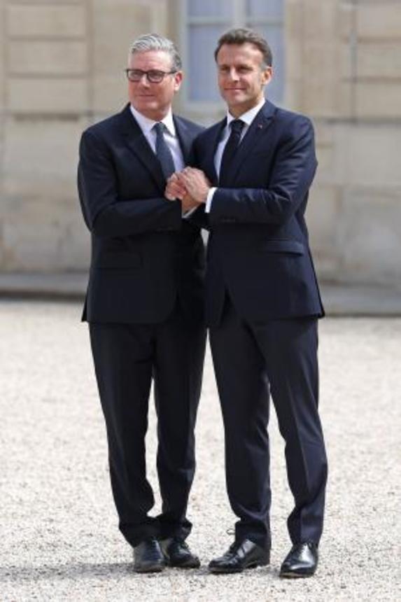 　パリのフランス大統領府で、会合の前に英国のスターマー首相（左）を出迎えるフランスのマクロン大統領＝１７日（ロイター＝共同）