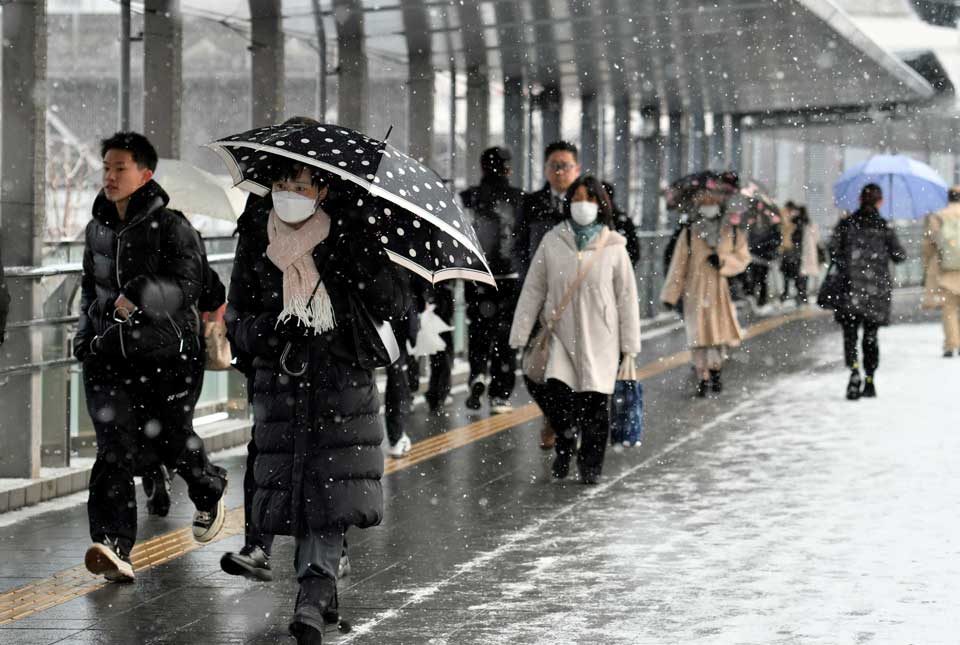 雪が降る中を出勤する人たち＝５日午前７時３５分、岐阜市神田町