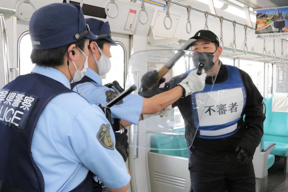 電車内の訓練で警察官に切りかかる不審者役＝大垣市高屋町、ＪＲ大垣駅