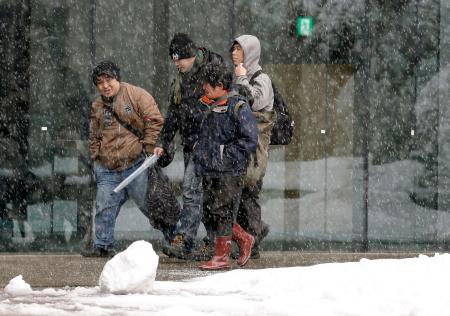 　雪が降る新潟県長岡市内を歩く人たち＝２０日午後