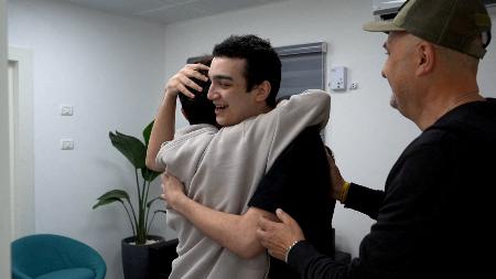 　１２日、イスラム組織ハマスに解放され、家族と抱き合う人質の男性＝イスラエル南部レイム（イスラエル首相府提供、ロイター＝共同）