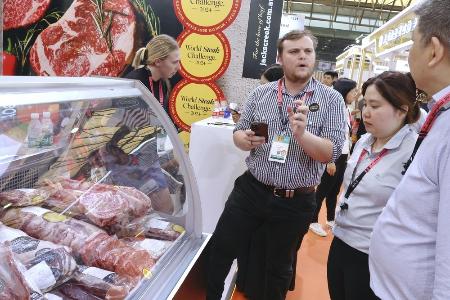 　中国最大級の食品見本市で、自国産牛肉を中国のバイヤーに売り込むオーストラリアの業者（左）＝５月、中国上海市