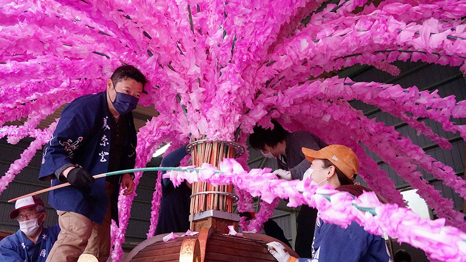 和紙の花が巻き付けられた「しない」を取り付ける美濃花みこし連のメンバー＝美濃市相生町