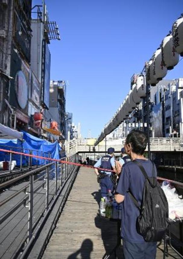 　消防隊員２人が犠牲になった大阪・道頓堀のビル火災現場で手を合わせる男性＝１９日午後