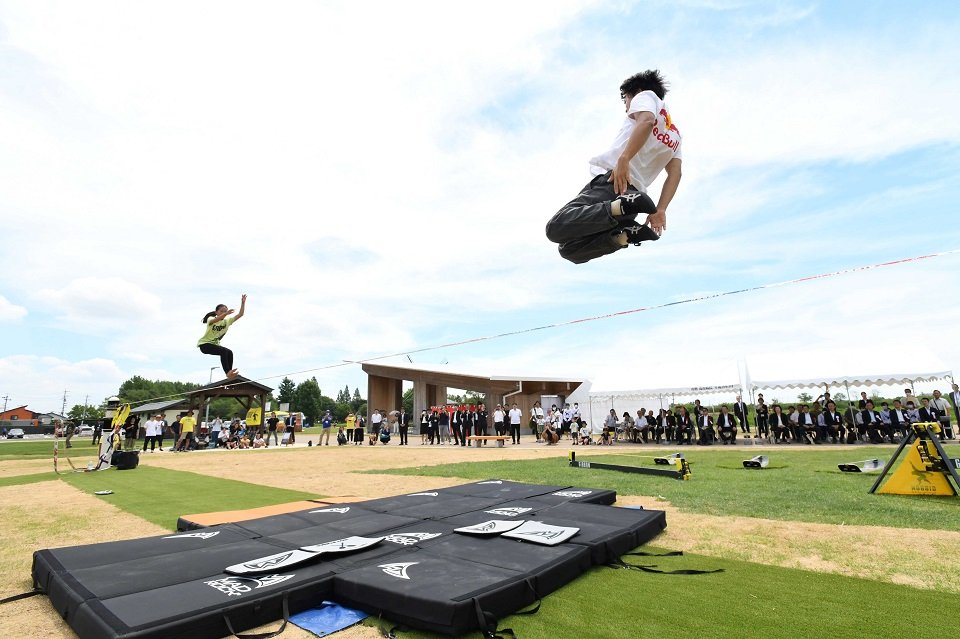 追加開園した芝生広場のスラックラインパークでパフォーマンスを披露するプロ選手＝海津市海津町福江、国営木曽三川公園アクアワールド水郷パークセンター
