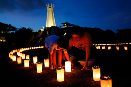 　沖縄全戦没者追悼式の前夜祭で、ろうそくに火をともす親子＝２２日夕、沖縄県糸満市の平和祈念公園