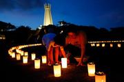 　沖縄全戦没者追悼式の前夜祭で、ろうそくに火をともす親子＝２２日夕、沖縄県糸満市の平和祈念公園