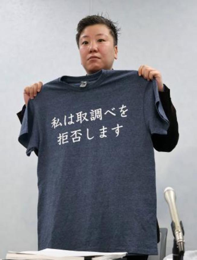 　勾留中の男性が着ていた「私は取調べを拒否します」と記されたＴシャツを手にする松本亜土弁護士＝１日午前、大阪市北区