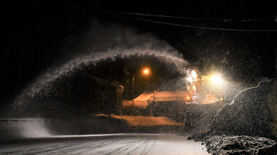 沿道によけた雪をかき出すロータリー除雪車。吐き出す雪が、路上に白いアーチを描く＝飛騨市古川町数河、国道４１号