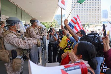　４日、米ロサンゼルスの連邦合同庁舎前で、警戒に当たる海兵隊員らに抗議する人たち（共同）