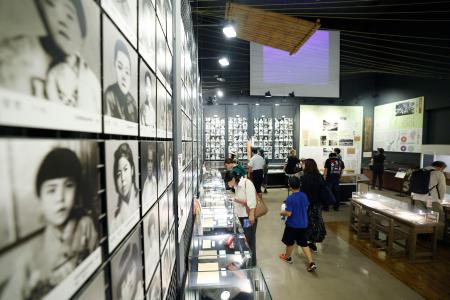 　「対馬丸記念館」で展示を見る人たち＝２１日午前、那覇市