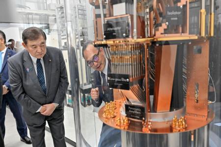 　産業技術総合研究所の量子・ＡＩ融合技術ビジネス開発グローバル研究センターで、超電導型量子コンピューターの内部模型を前に説明を受ける石破首相（左）＝１８日午後、茨城県つくば市（代表撮影）