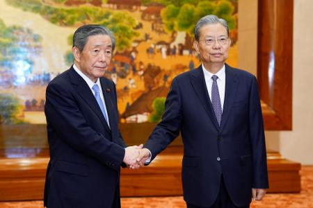 　中国共産党序列３位の趙楽際・全人代常務委員長（右）と握手する日中友好議員連盟の森山裕会長＝２９日、北京の人民大会堂（共同）