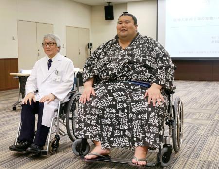 　体重３００キロまで対応できる超特大の車いす（右）に試乗する現役最重量の三段目出羽ノ城さん＝１１日午前、名古屋市