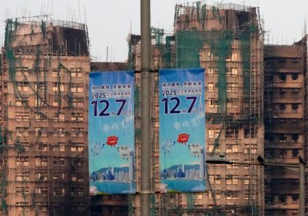 　火災のあった高層住宅群（奥）の近くに掲げられた立法会選挙の投票を呼びかけるポスター＝５日、香港（共同）