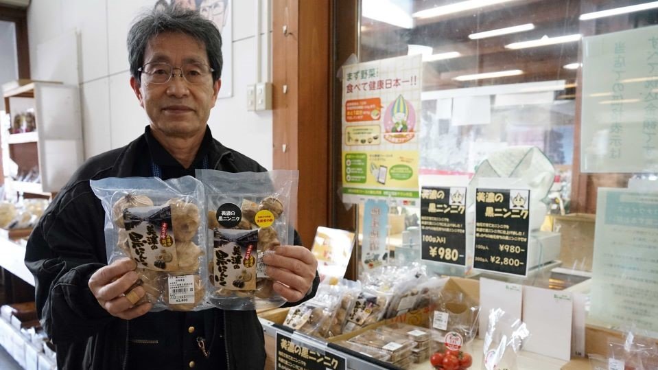 「美濃の黒にんにく」を手に特産品化に意欲を示す三輪治男駅長＝美濃市曽代、道の駅美濃にわか茶屋