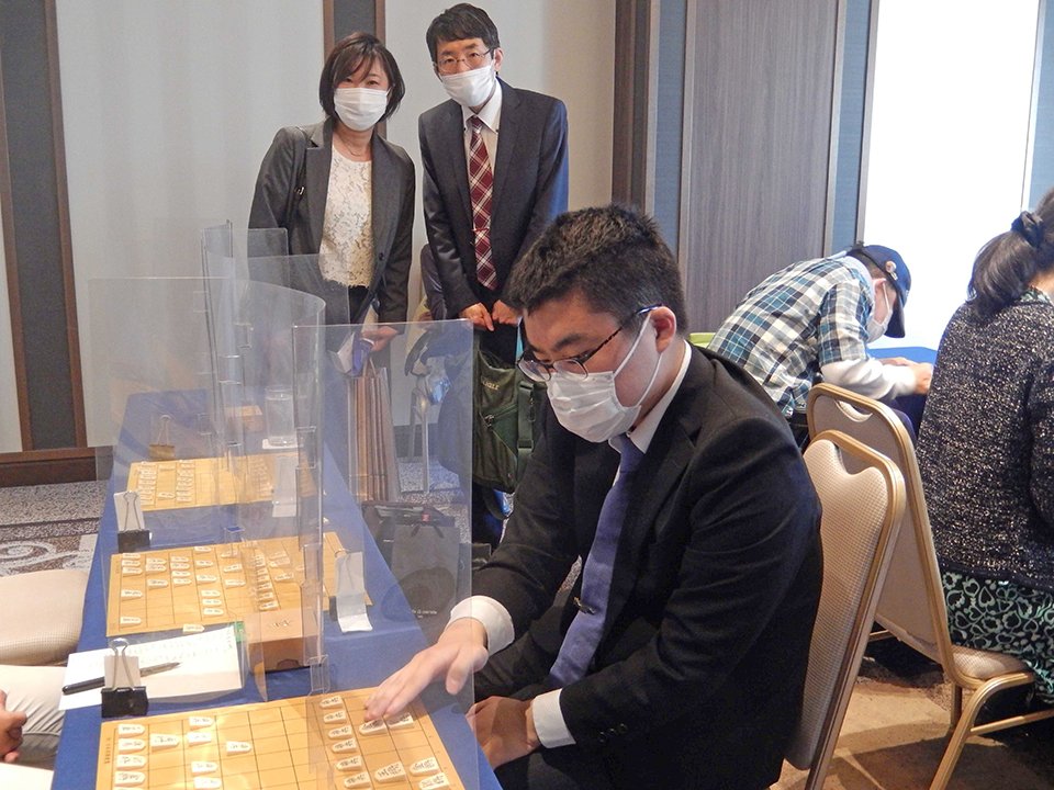 森一門祝賀会で指導対局する高田明浩さんと、見守る両親。師匠の森信雄さんが撮影した＝２０２２年５月４日、大阪市内のホテル