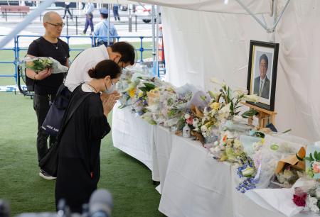 　安倍元首相銃撃事件から３年、現場付近に設置された献花台で手を合わせる人たち＝８日午前、奈良市