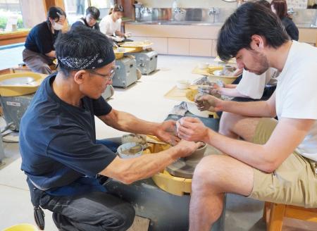 　「駿府の工房匠宿」で体験者（右）に陶芸を教える職人＝１７日、静岡市