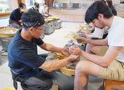 　「駿府の工房匠宿」で体験者（右）に陶芸を教える職人＝１７日、静岡市