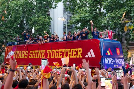 　２０日、サッカーＷ杯で優勝したスペイン代表選手らを乗せたバスを歓迎する市民ら＝マドリード（共同）