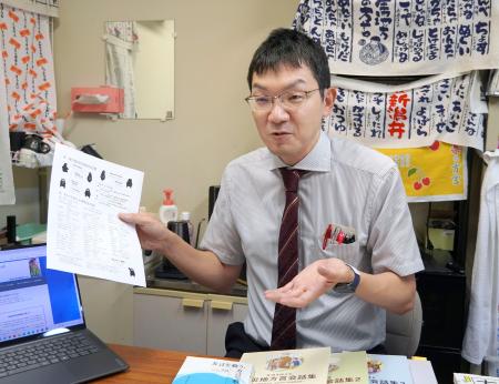 　熊本方言をまとめたパンフレットを手に取材に応じる東北大の中西太郎准教授＝８月、仙台市