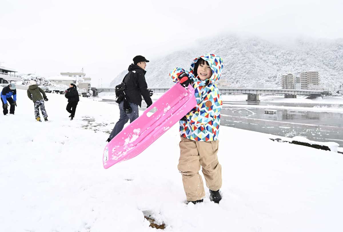 初積雪でそり遊びを楽しむ子ども＝１２日午前８時４９分、岐阜市の長良川堤（撮影・堀尚人）