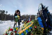 　ロシアのウクライナ侵攻開始から４年となった２４日、首都キーウ近郊イルピンにある墓地で、戦没した息子の墓に献花する女性（共同）