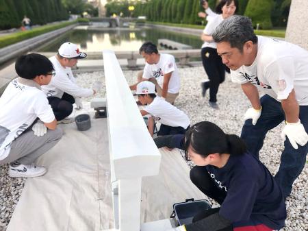 　広島市の平和記念公園で柵を白く塗るボランティア＝２０２５年７月（塗魂ペインターズ事務局提供）