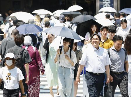 　日傘を差して歩く人たち＝２０２５年７月、東京都新宿区