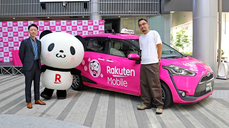 ピンクのラッピングタクシーの前で鐙一義事業開発部長（左）と成栗稔社長＝岐阜市徹明通、柳ケ瀬グラッスル３５
