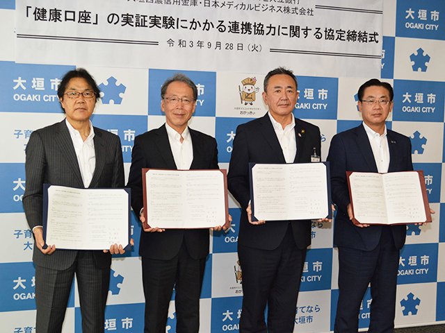 健康口座の実証実験に関する連携協定を交わす（右から）栗田順公理事長、石田仁市長、境敏幸頭取ら＝大垣市役所