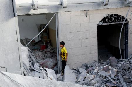 　２２日、ガザ南部ハンユニスで、イスラエル軍の攻撃により破壊された家屋に立つパレスチナ人の子ども（ロイター＝共同）