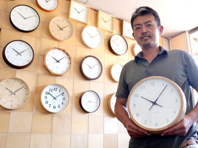 ホワイトアッシュの無垢材を使った木枠時計を披露する加藤隼人社長。一番人気の商品だ＝郡上市八幡町稲成、加藤木工